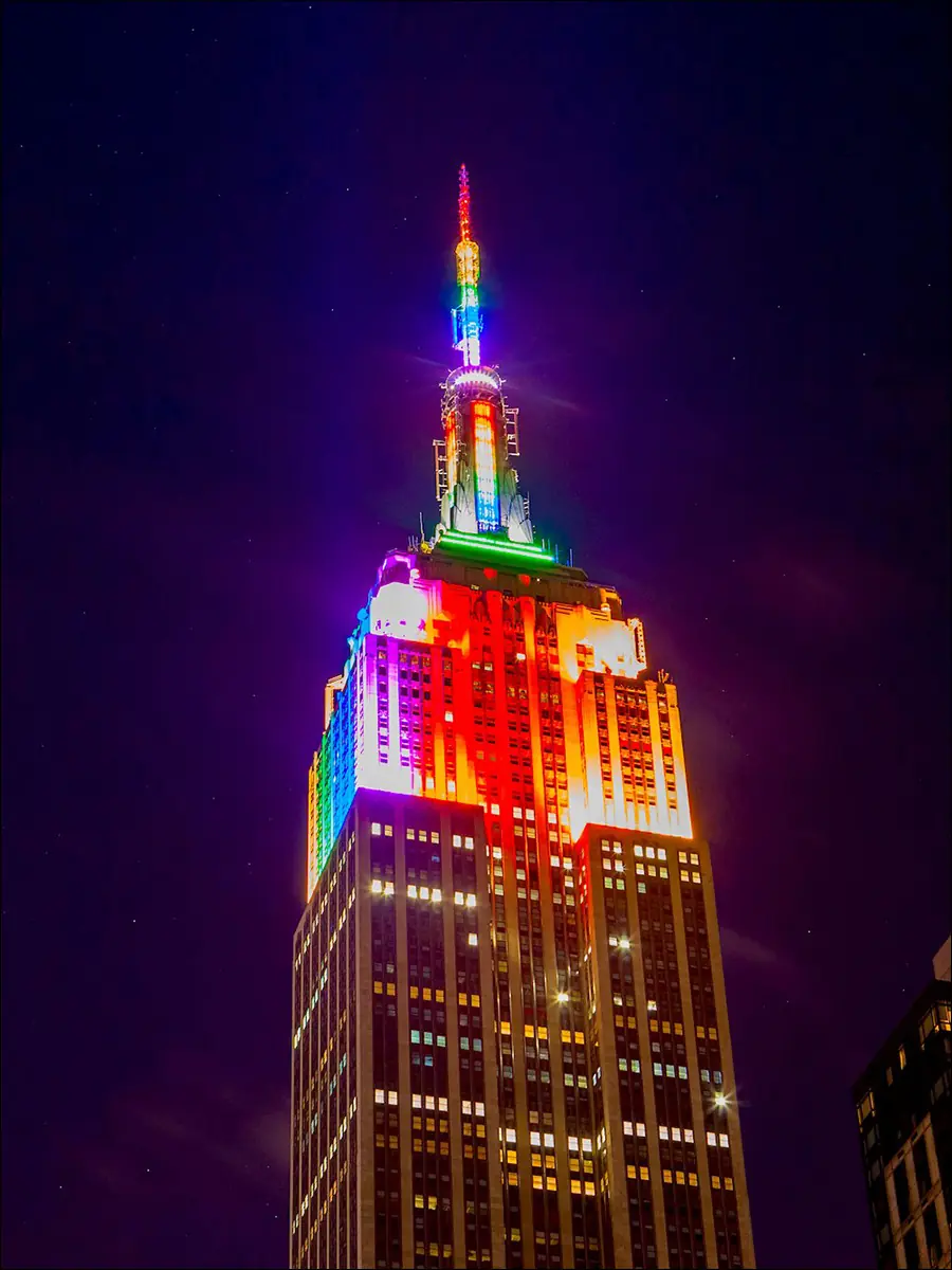 Освещенное разноцветными прожекторами здание Эмпайр Стейт Билдинг